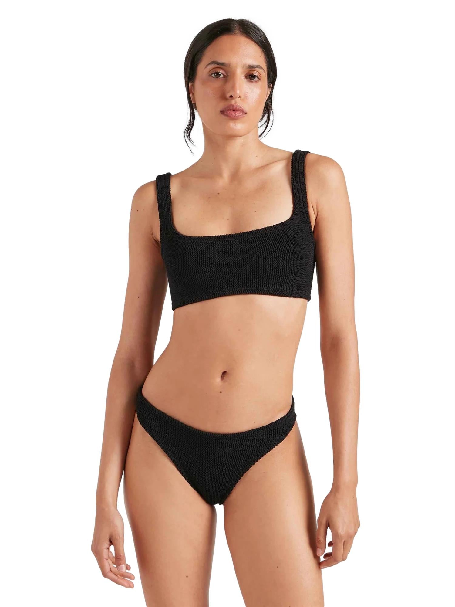 Sort Hunza G Xandra bikinibikini av elastisk stoff, vist på en modell i en solrik strandsetting.