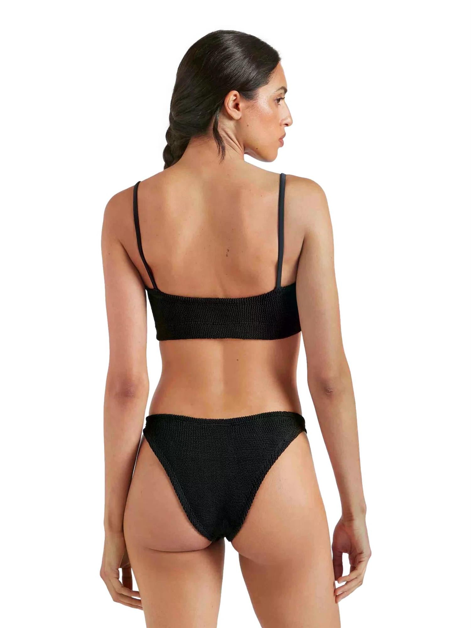 Sort Hunza G Gigi bikini i strikket stoff med svømmelignende design og tynn stropp, vist på en modell mot lys bakgrunn.