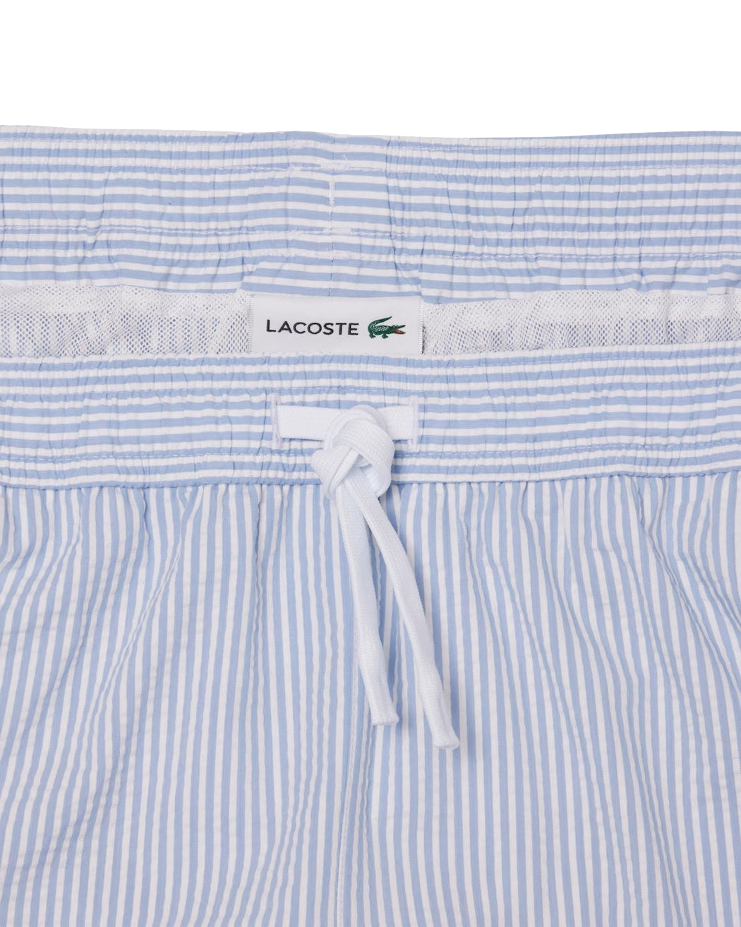 Lacoste badetøy, mid-length stripete svømme-badeshorts med tekstur i hvitt og blått, vist på en modell.