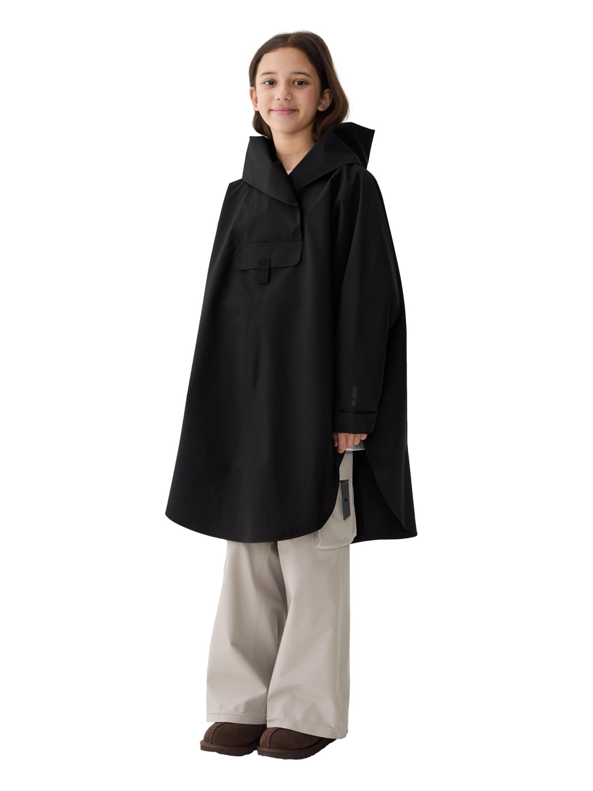 Blæst Bergen Mini Poncho jakke i svart, vises på modell med hette og lukkede fronter, perfekt for værbeskyttelse.