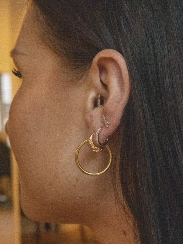 Gullfargede Maria Black Senorita 20 hoops øredobber som henger elegant i øret, laget av høykvalitets gull.
