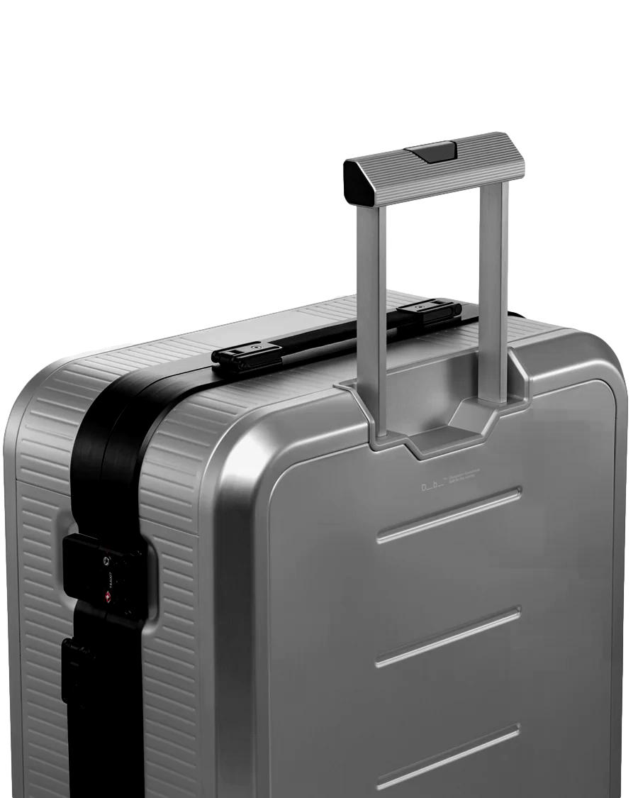 Db Ramverk Alu Check-In koffert i sølv og sort, medium størrelse, robust aluminiums bagasje med hjul og teleskothåndtak.