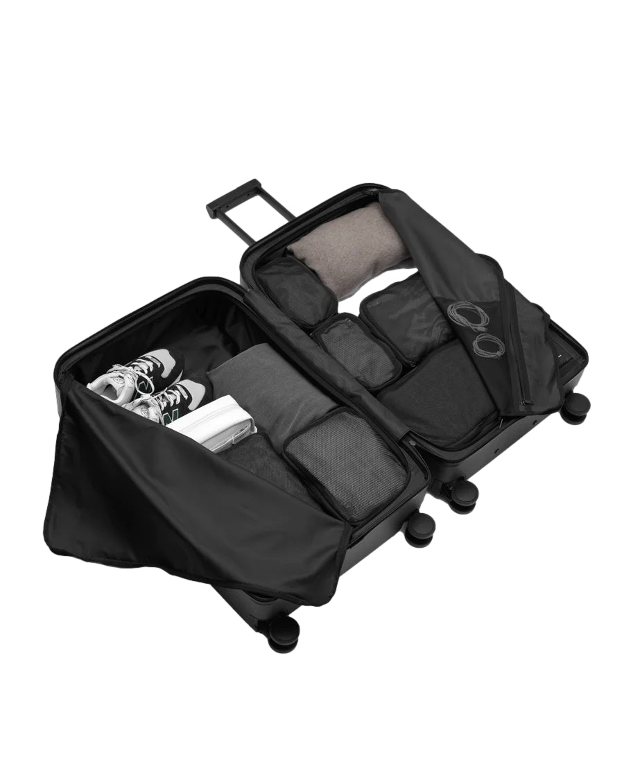 Sort Db Ramverk Check-In Medium koffert med harde sider og hjul, klar til reise.