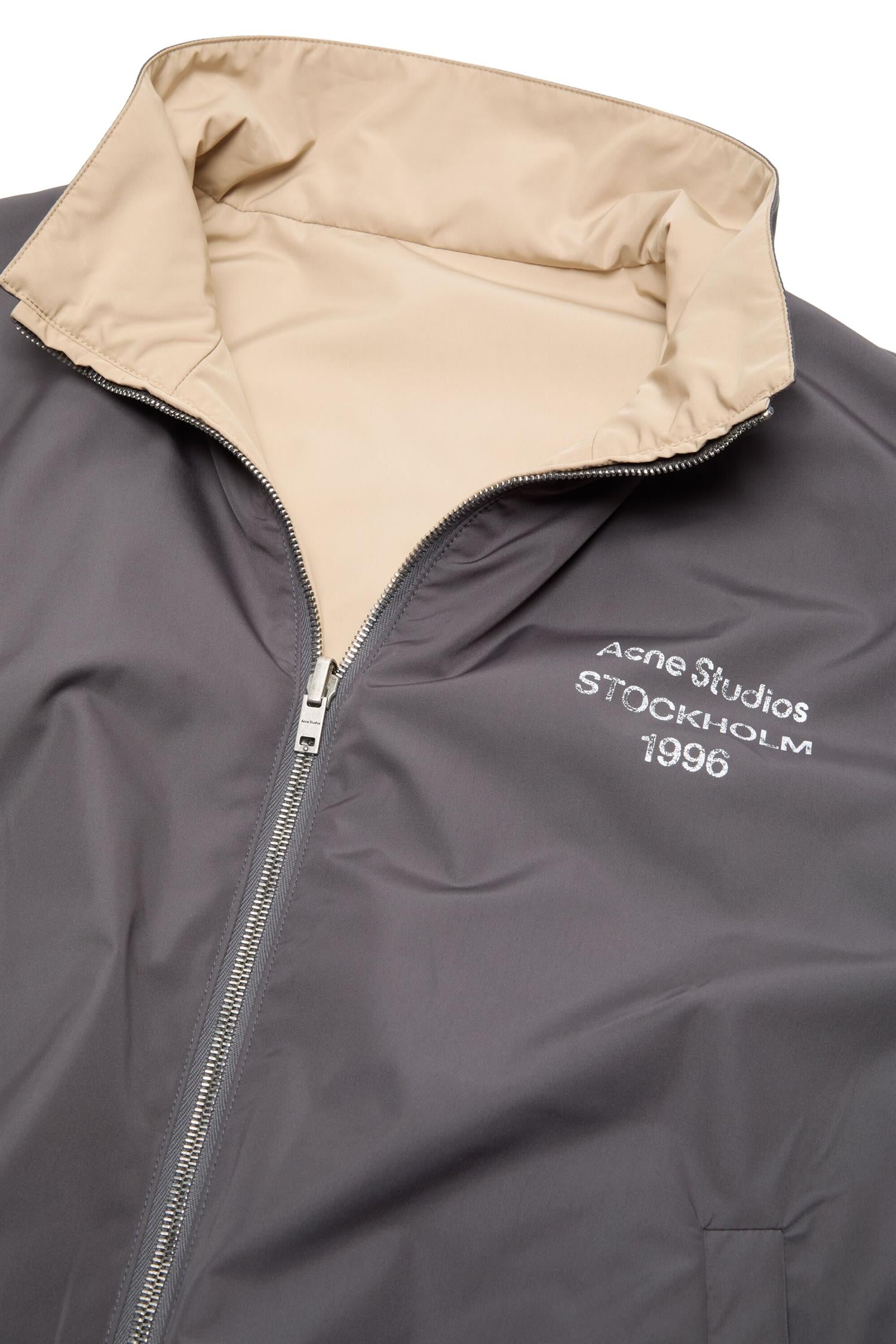 Beige Acne jakke med reversible logo-design, vises med lukket front og casual passform, laget av mykt stoff.