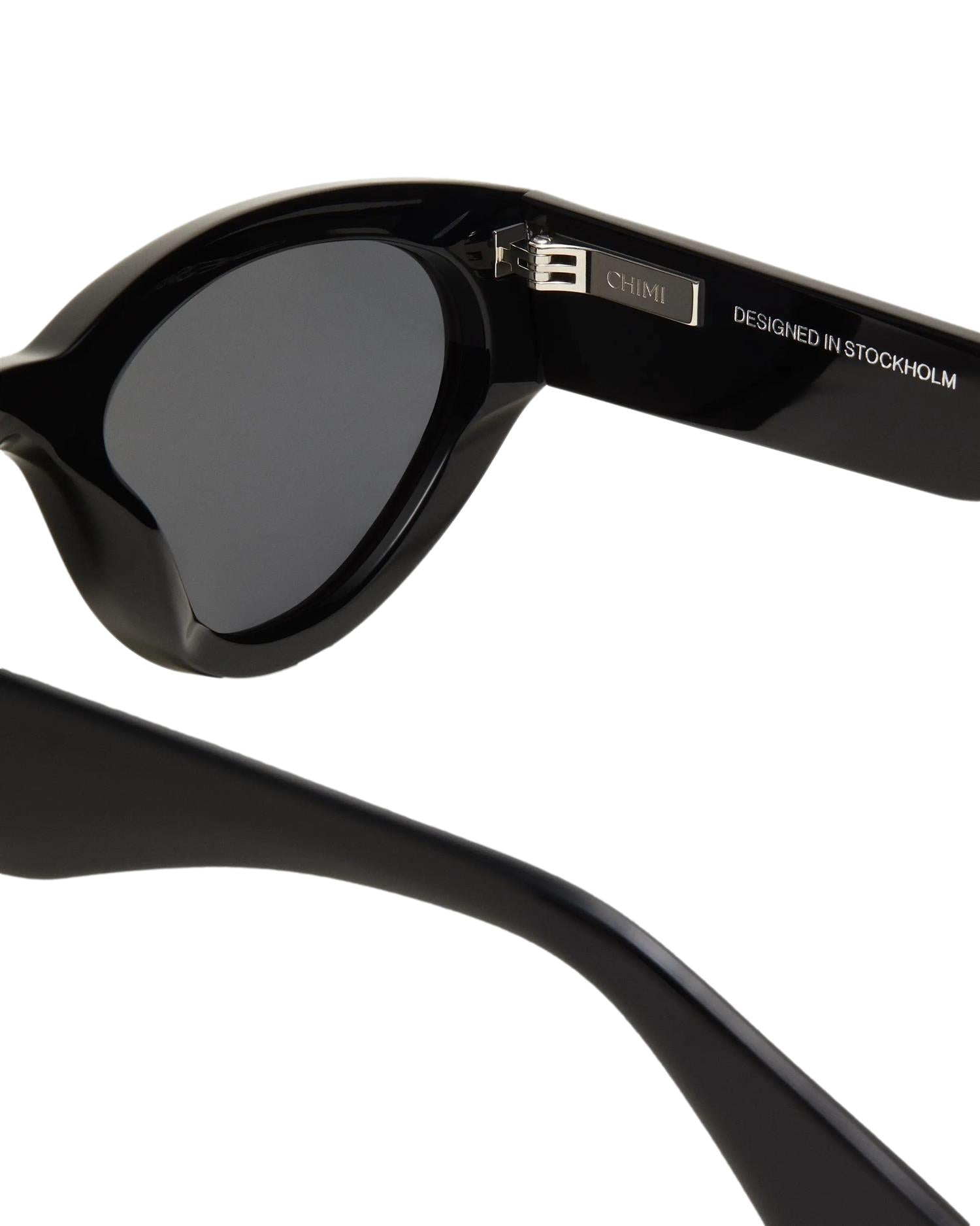 Chimi Eyewear 06 svarte solbriller med runde glass og svart innfatning, stilfullt tilbehør for solskinnsdager.