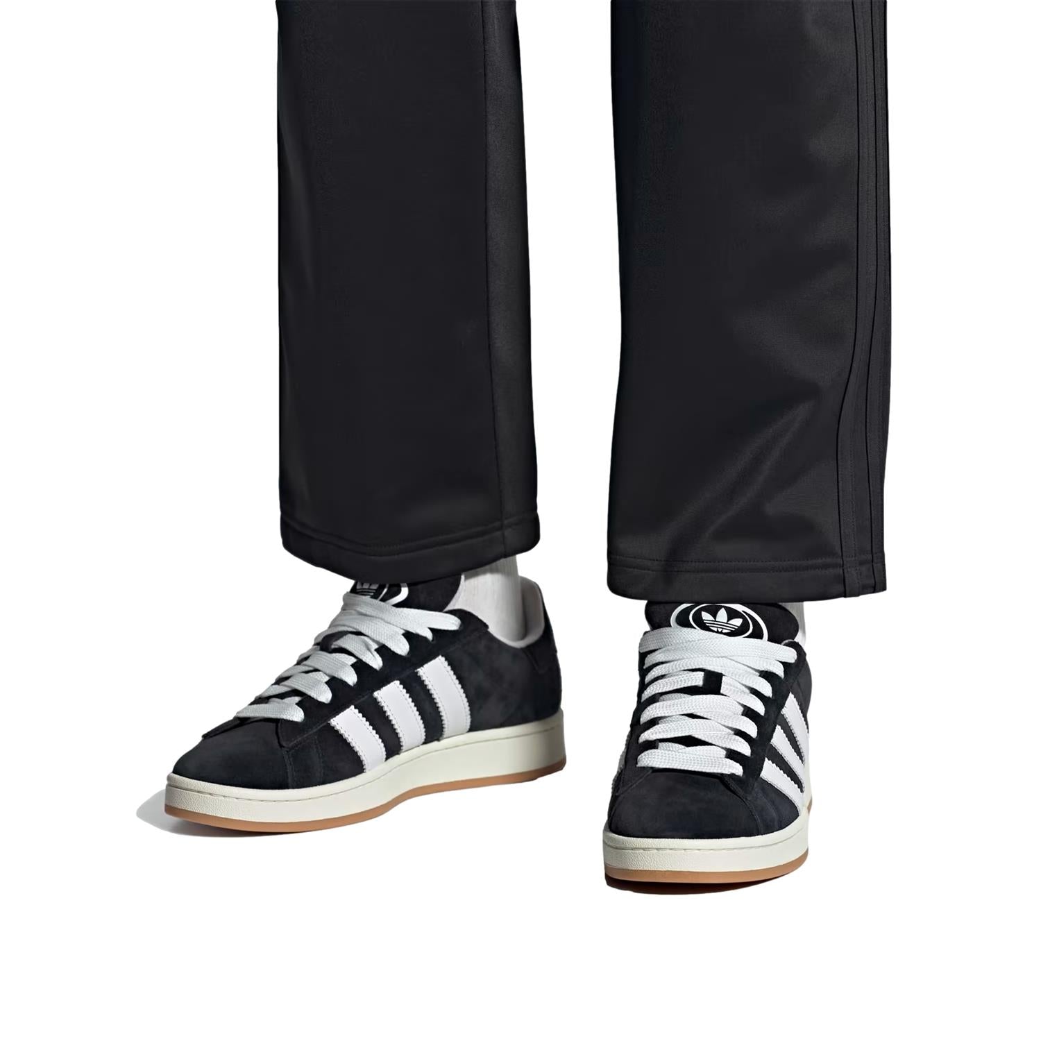 Sort Adidas Campus 00s sko med klassisk design og hvite detaljer, vist på en person som går på gaten.