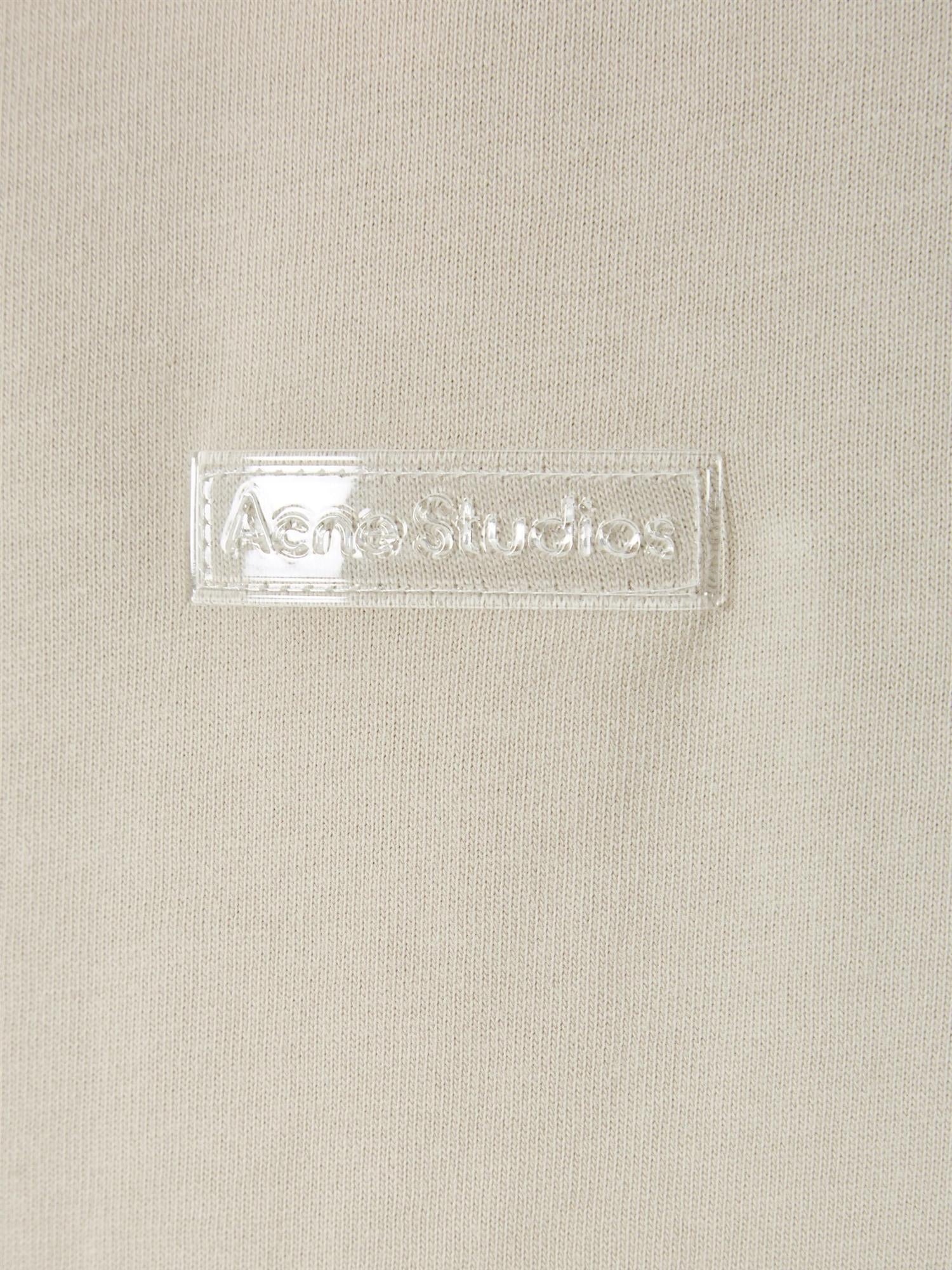 Beige Acne Cotton Crewneck T-skjorte som viser t-skjortens myke bomullsstoff og klassiske rundhalsdesign.