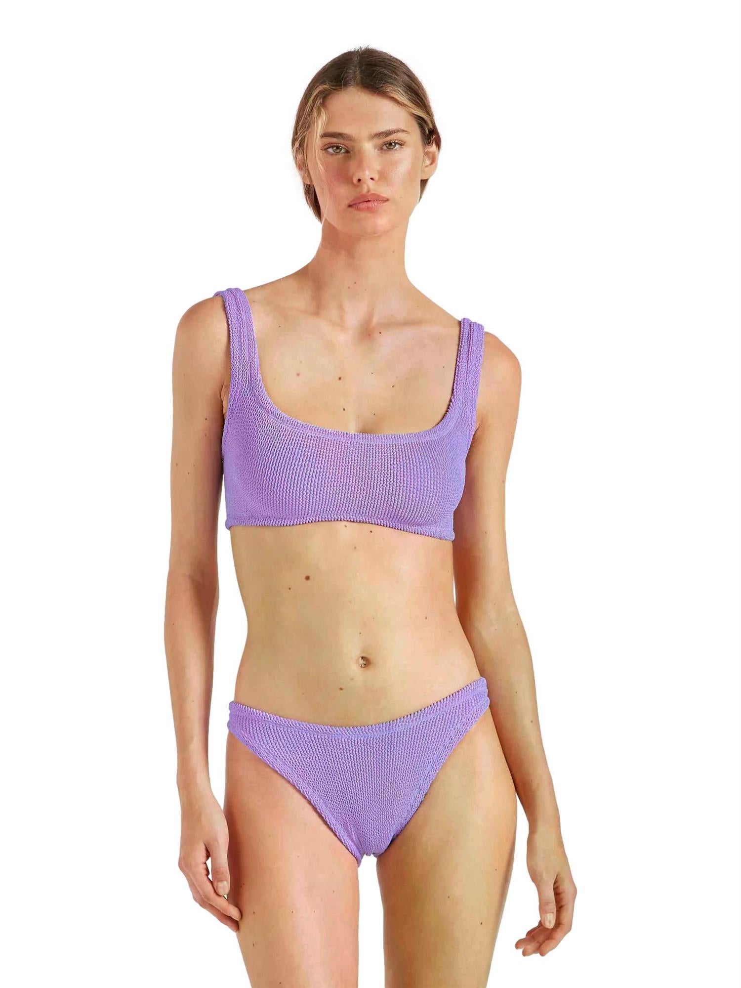 Hunza G Xandra bikini i lilla, tettsittende badetøy med glatt, elastisk stoff og bred skuldersnor, vist på modell.