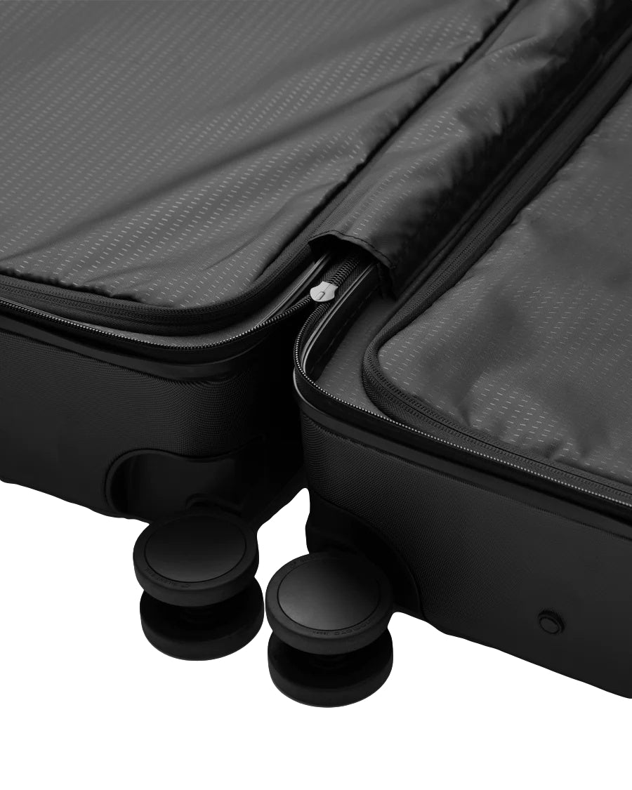 Sort Db Ramverk Check-In koffert med fire hjul og utvidbart design, laget av robust materiale for reise.