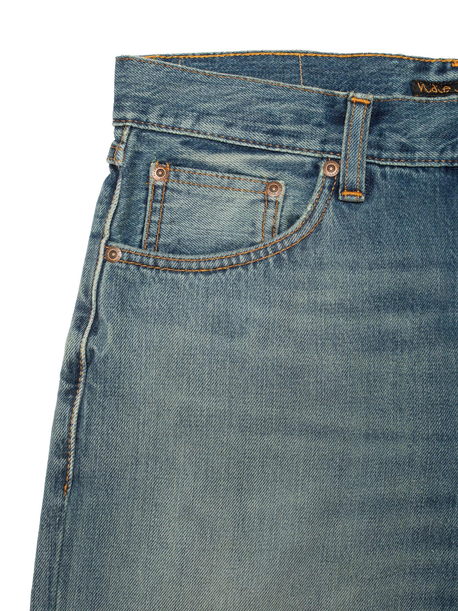 Nudie Jeans Rad Rufus jeans i beige og blå med slitte detaljer og slim passform, vist på en modell.
