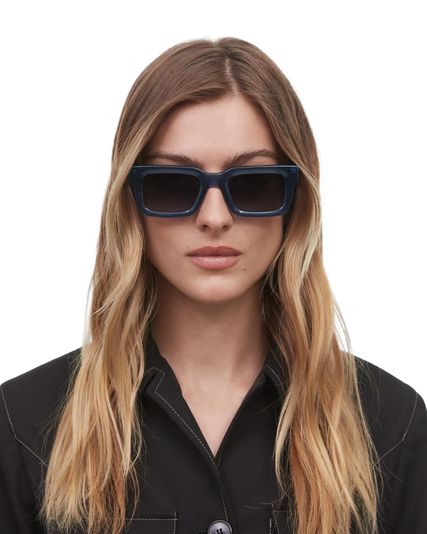 Chimi Eyewear 05 Indigo solbriller med blå ramme og store solbrilleglass, mot en lys bakgrunn