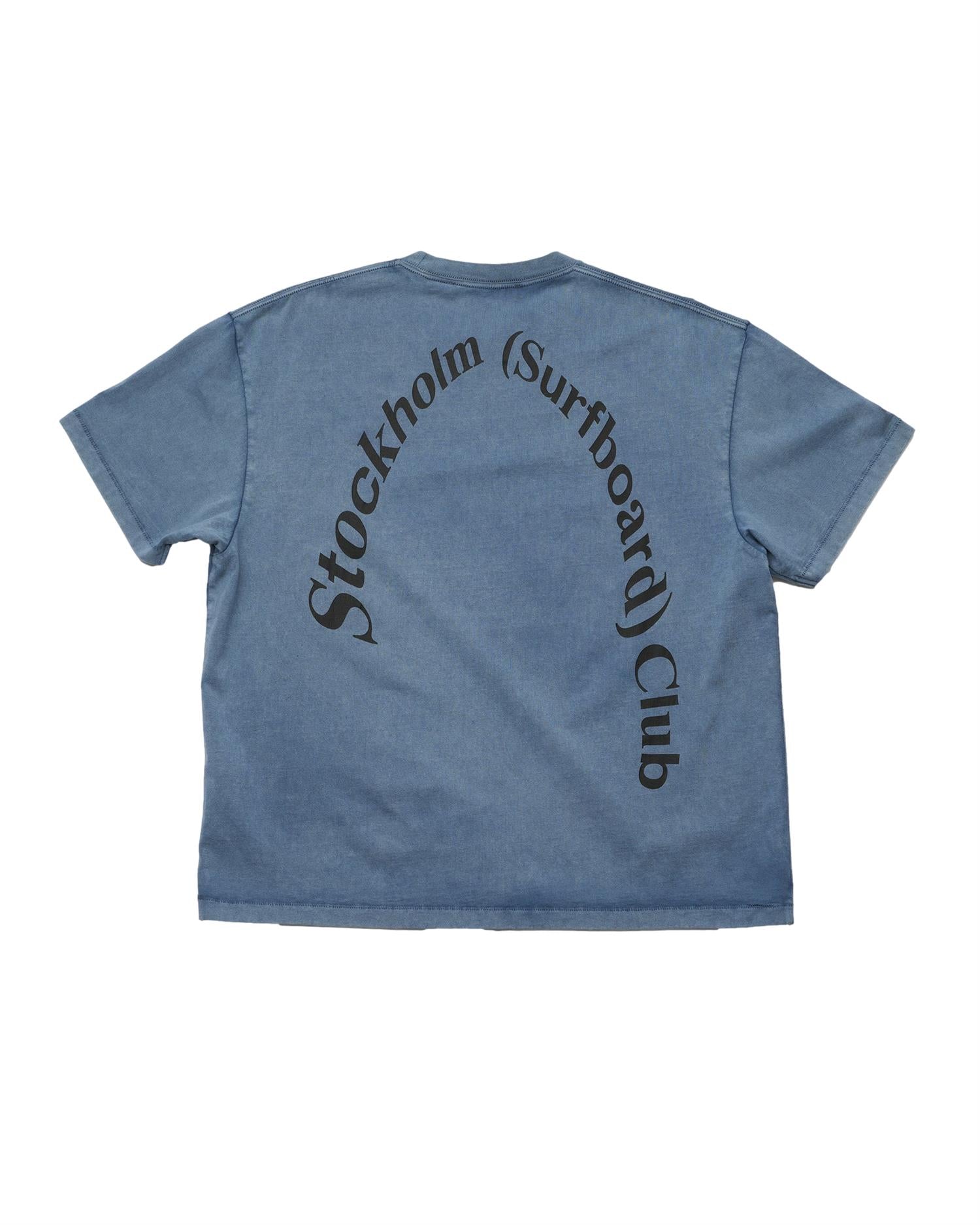 Blå Stockholm Surfboard Club T-skjorte med stor logo på ryggen, mykt bomullsstoff, casual surfestil.