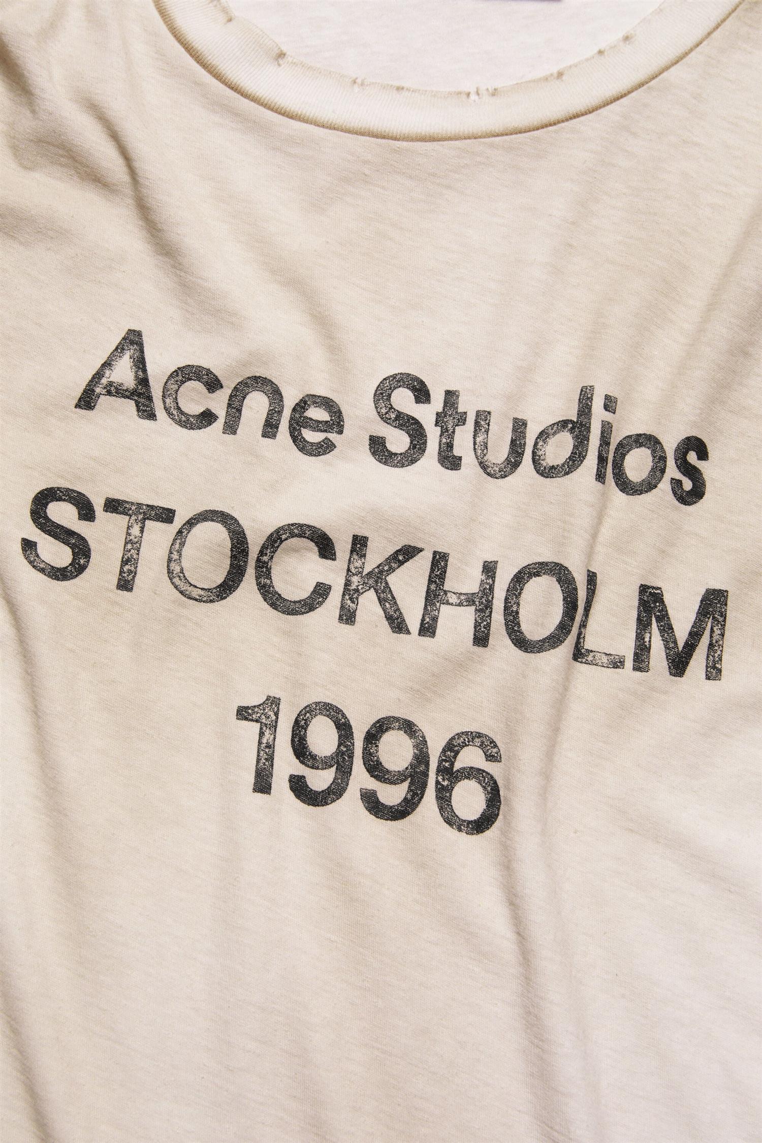 Acne logo T-skjorte i melkehvit med spraydesign, komfortabel bomulls-T-skjorte for casual bruk.