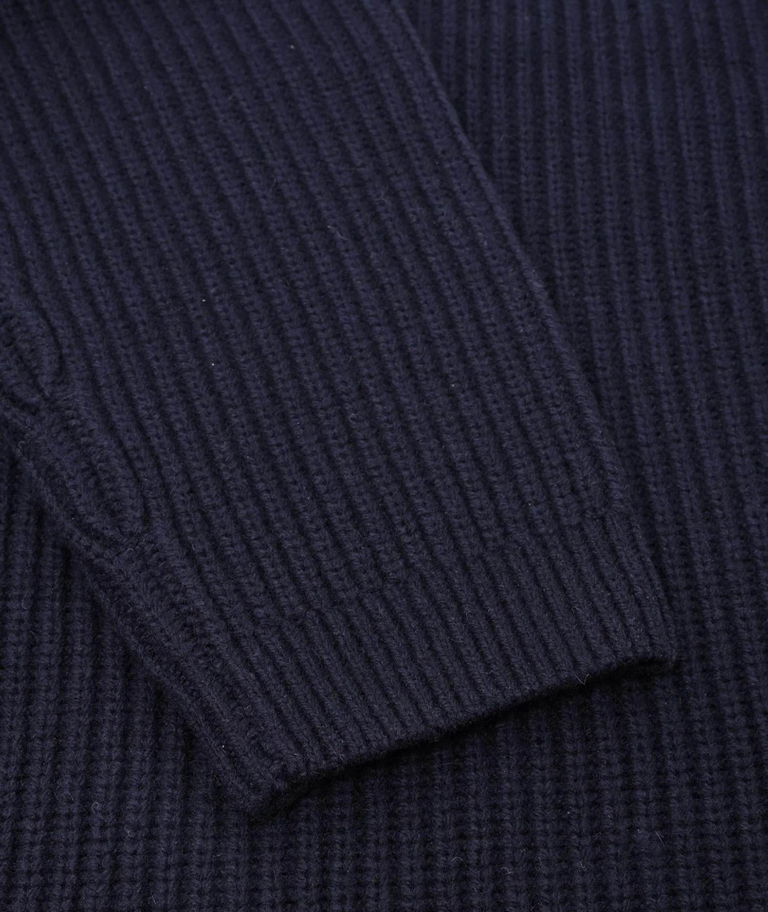 Navy ullgenser fra Garment Project med halvt glidelås og ribbede detaljer, vist på modell.