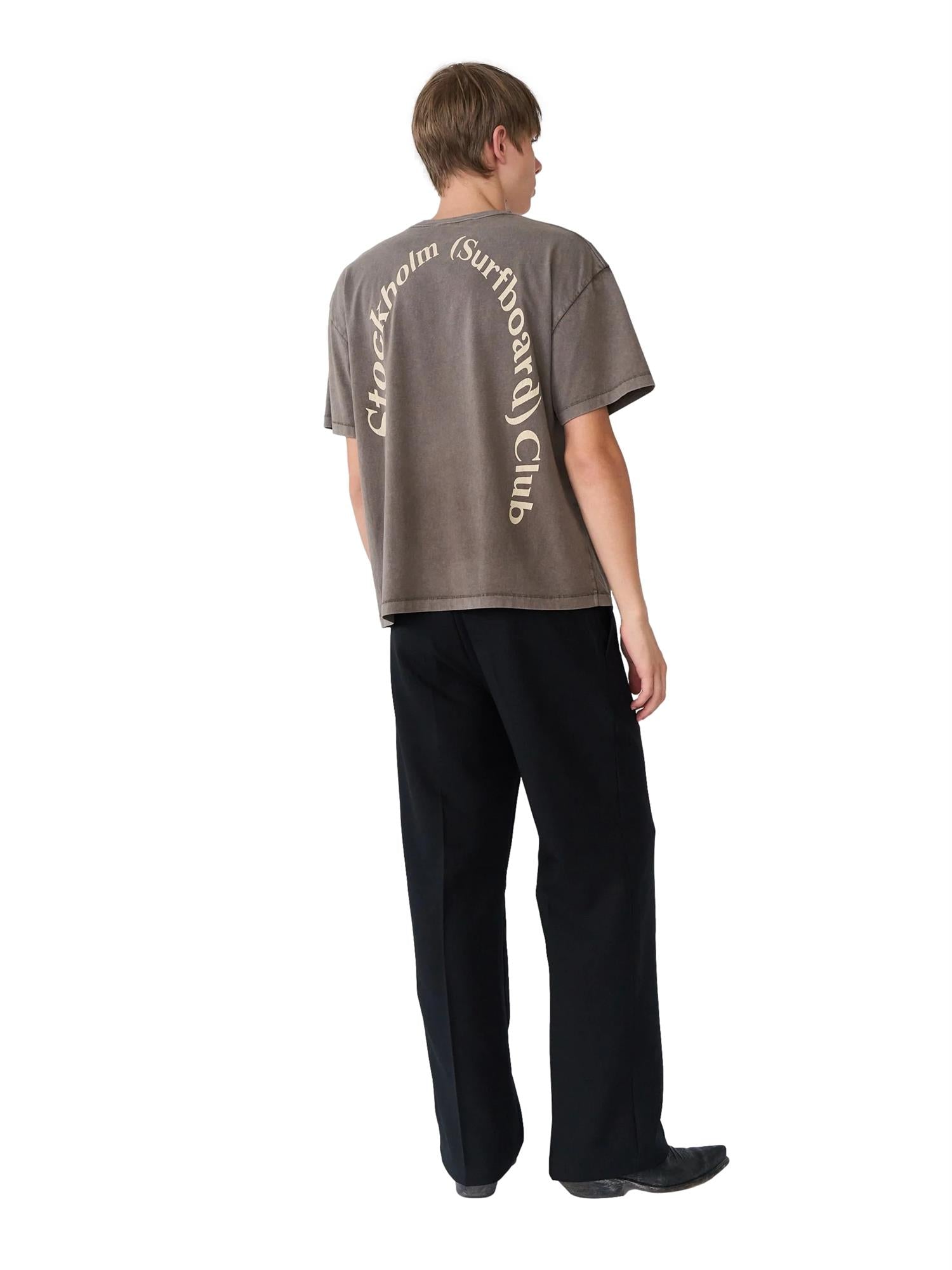 Brun Stockholm Surfboard Club Box Tee med logo på baksiden, casual T-skjorte i hickory, behagelig og stilfull for surfere.