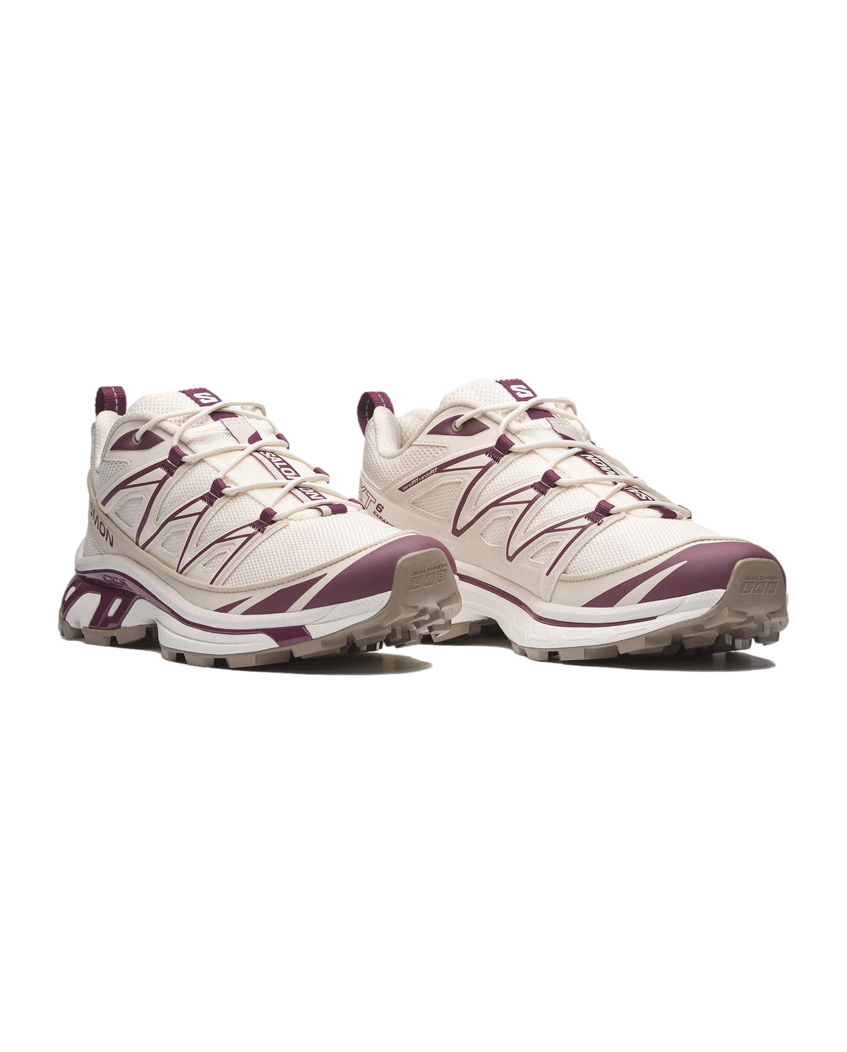 Salomon XT-6 Expanse joggesko i hvitt, burgunder og kremfarger med kontrastdetaljer, brukt utendørs.