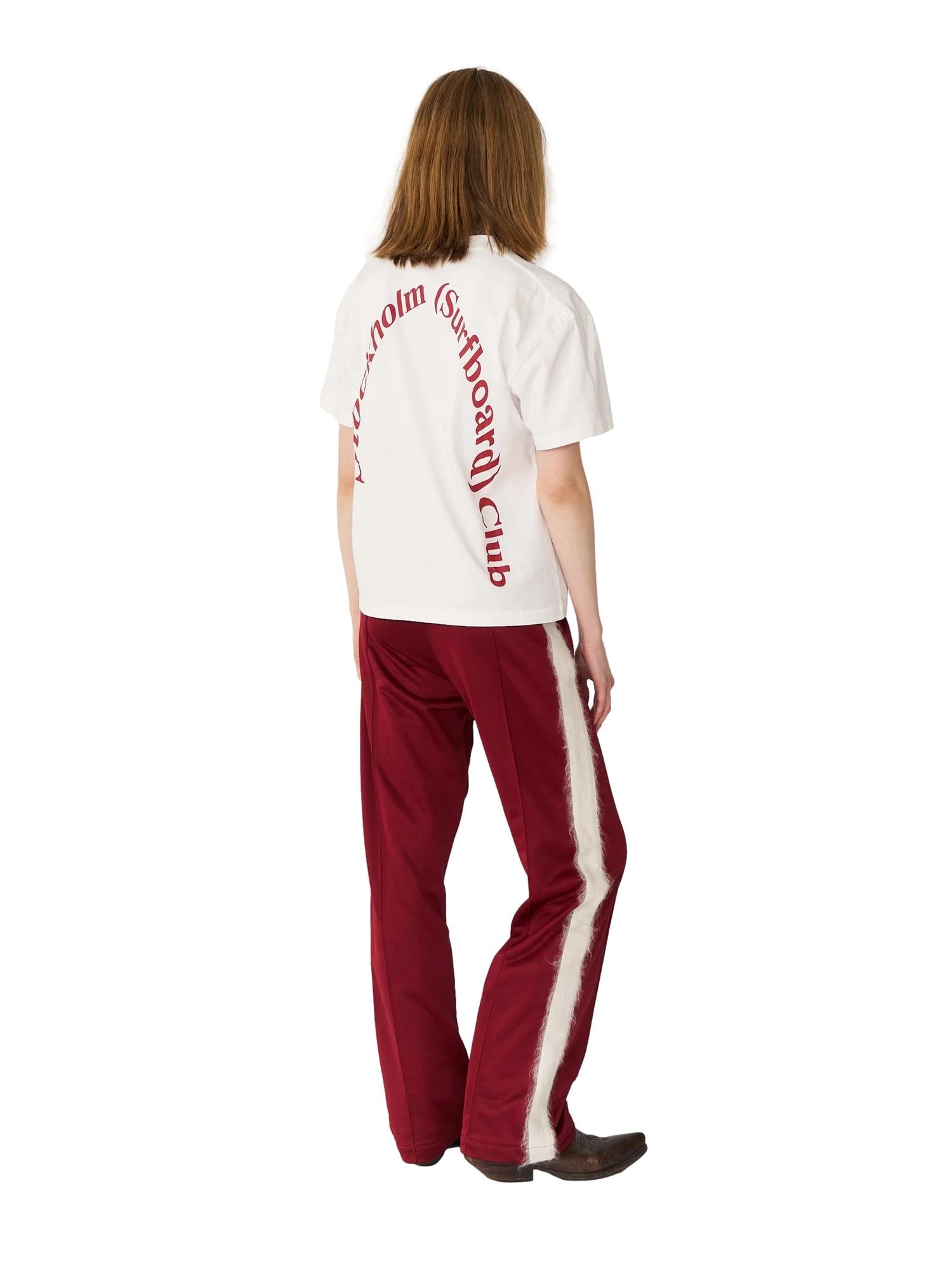 Hvit T-skjorte fra Stockholm Surfboard Club med stor logo på ryggen, casual klesplagg for surfentusiaster.