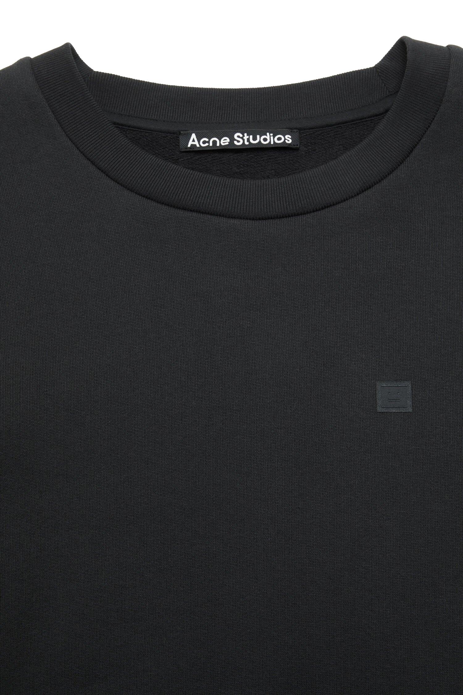 Sort Acne genser med rund hals og fleece-materiale, med ansiktsdesign på forsiden, komfortabel og stilfull.