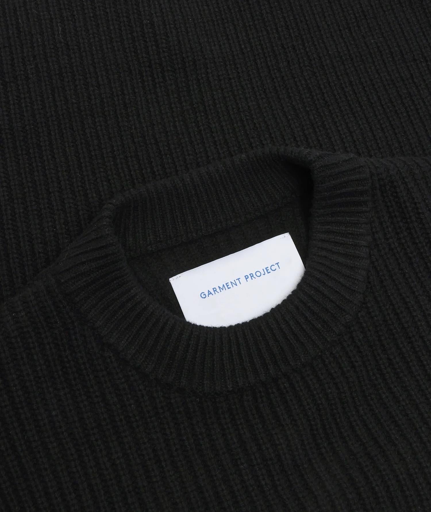 Sort genser fra Garment Project i boxy ullstrikk, vist på modell, med rund hals og lang erme, myk og komfortabel.
