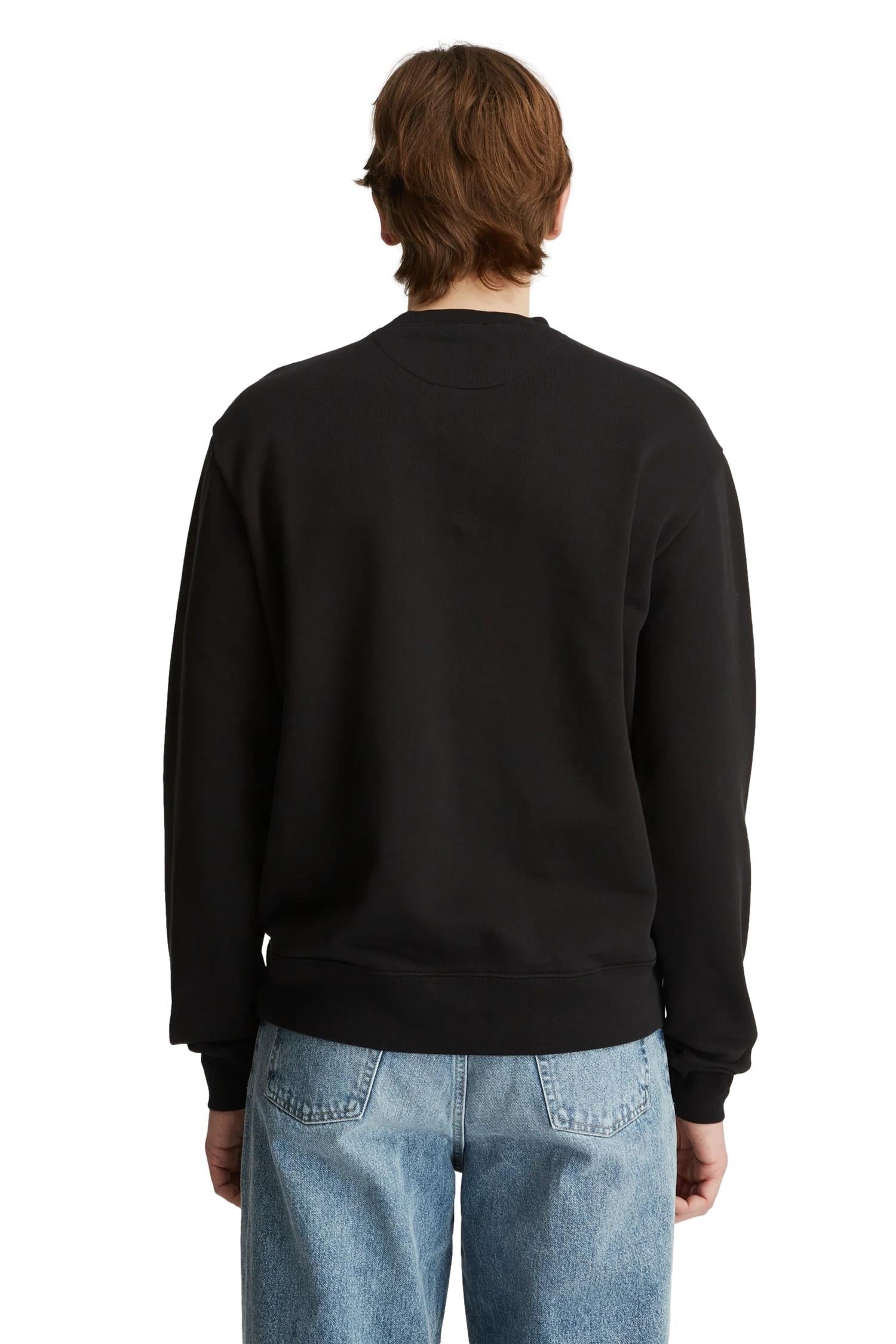 Livid Palmer svart genser med rund hals og lange ermer, vist på modell foran en nøytral bakgrunn.