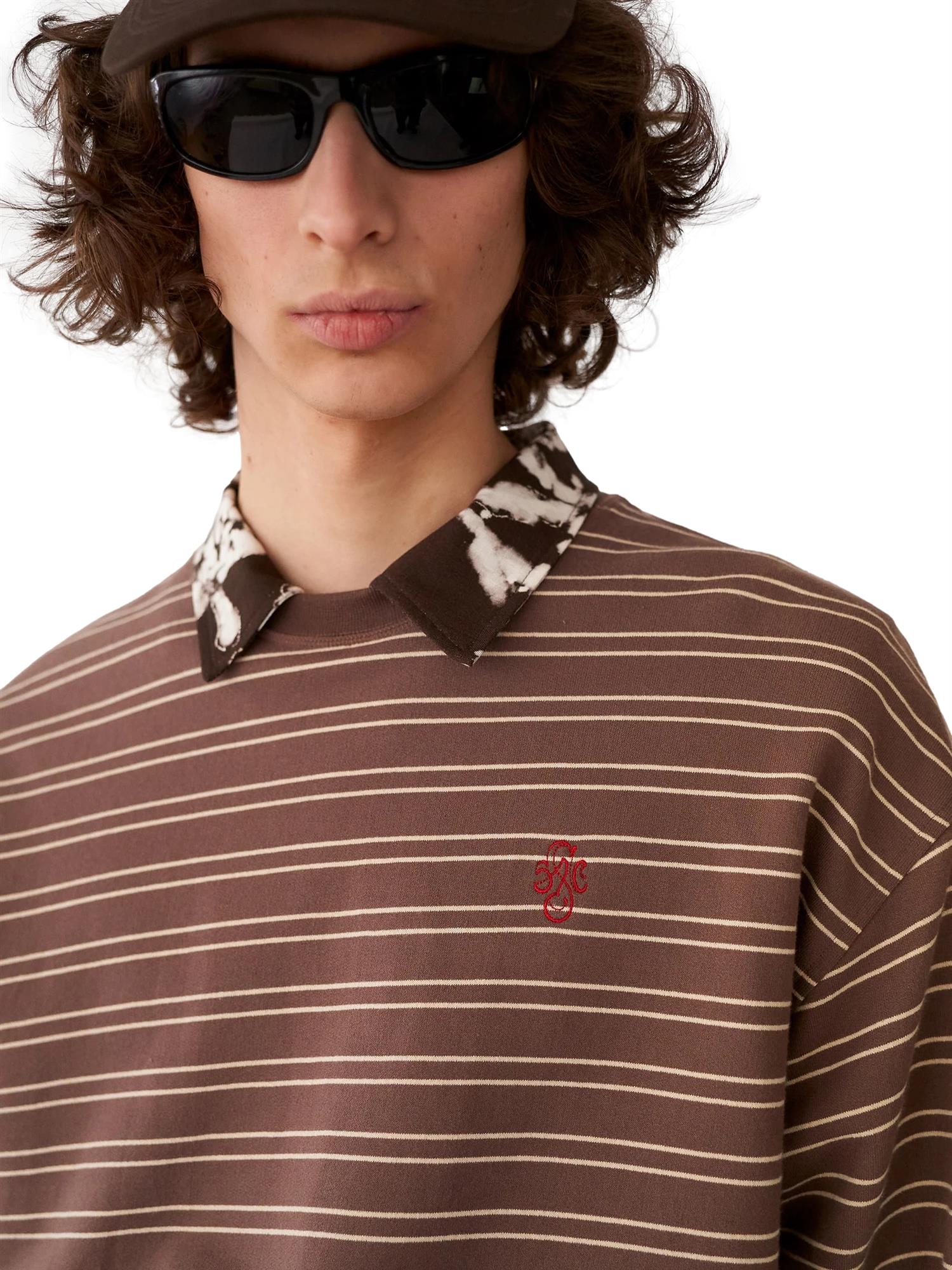 Brun Stockholm Surfboard Club Benny genser, komfortabel og stilig, vist på en modell foran en enkel bakgrunn.
